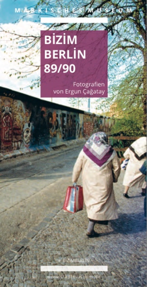 Ausstellungscover, auf dem zwei Frauen mit Kopftuch auf einem Weg neben der Berliner Mauer laufen